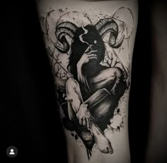 a black and white photo of a ram tattoo on the leg