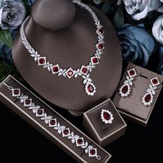 a necklace, bracelet and earring set with flowers in the background