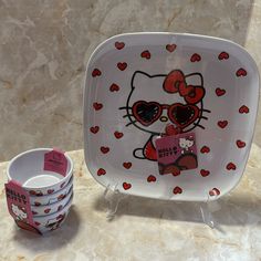 a hello kitty plate next to a cup and saucer on a marble counter top