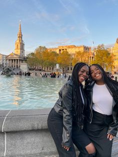 two women posing for a photo in front of a fountain