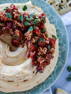 a blue plate topped with hummus and garnish on top of crackers