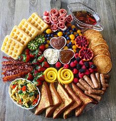 a platter with waffles, fruit, and other foods arranged in the shape of a circle