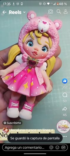 a hand holding a small doll in a pink dress