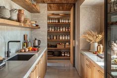 a kitchen with wooden cabinets and shelves filled with food on top of counter tops next to a sink