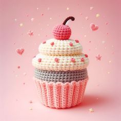 a crocheted cupcake with a cherry on top and sprinkles around it