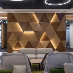 an office with couches and chairs in front of a wood paneled wall that has geometric shapes on it