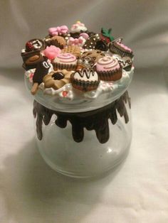 a glass container filled with lots of cupcakes on top of a white table