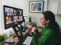 a woman sitting at a desk in front of a computer screen with people on it