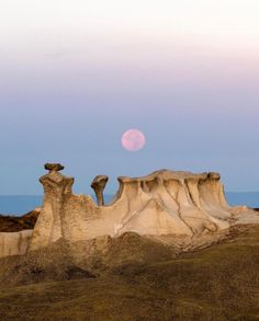 the moon is setting over an eroded landscape