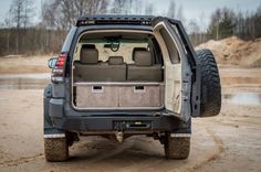 the back end of a vehicle with its doors open on a dirt road near water