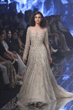 a model walks down the runway in an embellished gown