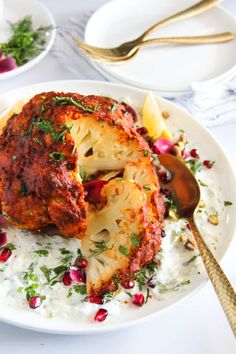 a white plate topped with meat covered in sauce and garnished with pomegranates