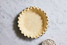 an uncooked pie crust next to a bowl with seeds