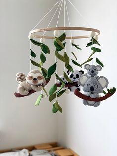 a mobile with two stuffed animals hanging from it's sides and leaves on the bottom