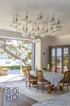 a dining room table and chairs in front of a large window with an ocean view