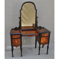 an antique vanity with mirror and stool inlaid to the top, on display against a brick wall