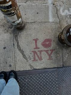 someone is standing on the sidewalk next to a fire hydrant and two beer bottles