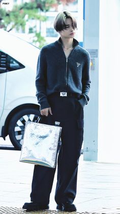 a young man is standing on the sidewalk holding a shopping bag