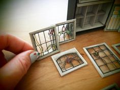 a hand is holding a pen and looking at three windows with stained glass in them