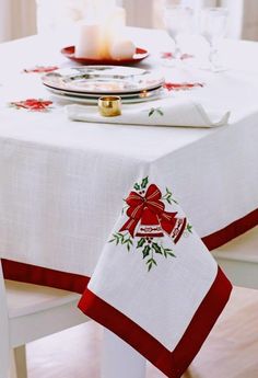 a white table with a red ribbon on it and a candle in the center,