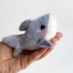 a hand holding a small stuffed animal in it's left hand with the eye open