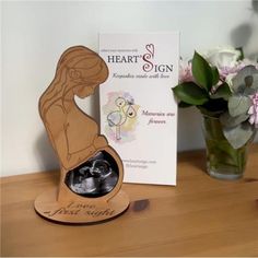 a wooden photo frame with a pregnant woman on it next to flowers and a card