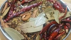 a metal bowl filled with lots of different types of vegetables and spices on top of a wooden table