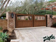 a brick driveway with a gate and trees in the background