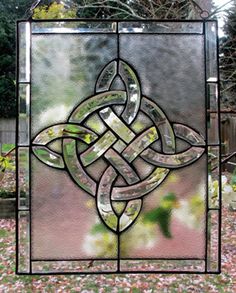 a stained glass window in the shape of a celtic knot, with pink flowers behind it