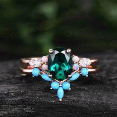 a ring with an emerald green stone surrounded by white and blue stones on top of it