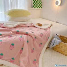 a bed with pink bedspread and pillows on top of it next to a basket