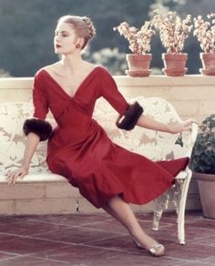 a woman in a red dress is sitting on a bench with her legs spread out