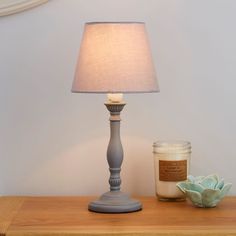 a table with a lamp and candle on it