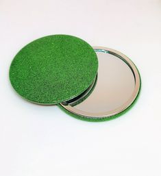 two green coasters sitting on top of a white table next to a round mirror