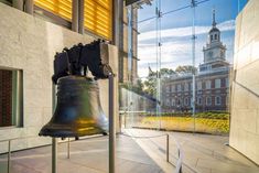 a large bell is in the middle of a room with glass walls and yellow flowers