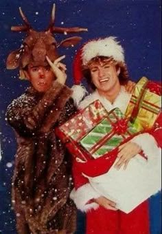 two people dressed as santa claus and reindeer holding presents