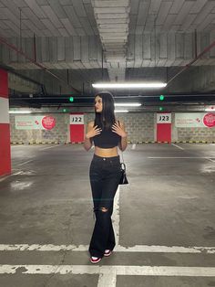 a woman is standing in an empty parking garage with her hands on her hips and looking up