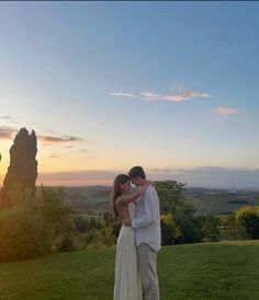 a man and woman standing on top of a lush green field next to each other