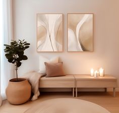 a living room with two paintings on the wall and some candles in front of it