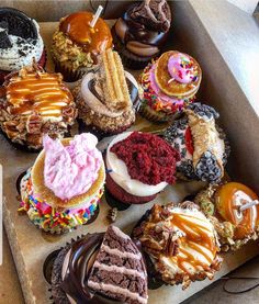 a box filled with lots of different flavored donuts on top of a table