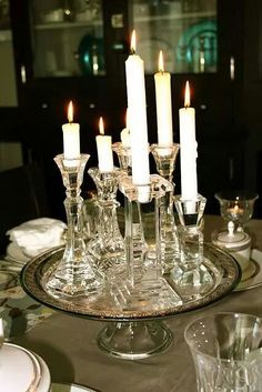 there are many candles that are lit on the table in front of the glassware