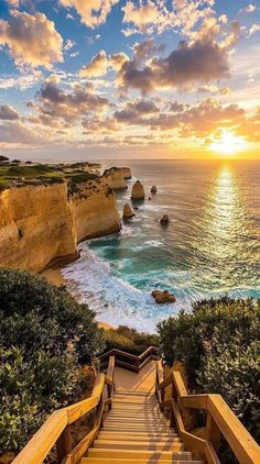 stairs leading down to the beach at sunset or sunrise over the ocean with cliffs in the background