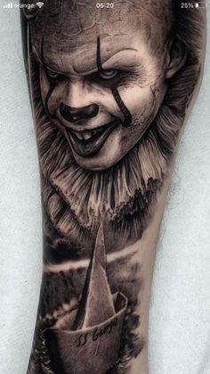 a man's leg with a creepy clown face on it and a boat in the water