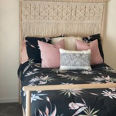 a bed with black and pink sheets, pillows and blankets on top of the headboard