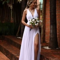 a woman in a white dress is standing on some steps and holding a flower bouquet