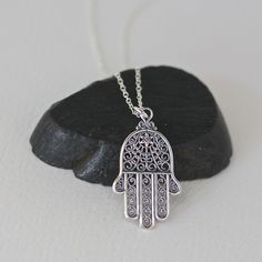 "A beautifully detailed Bali Silver Hamsa filigree charm simply dangles from a delicate silver chain. The chain measures 16\" with an extension to 18\" and is finished with a silver spring ring clasp. Please send a message if a different length chain is desired. The filigree detail in this charm is amazing! Hamsa Hand charm: 16x28mm Total length of pendant: almost 1 1/4\" Silver chain: 1mm All silver is sterling. As the owner, maker, designer, and curator of this shop, I take great pride in prov Sterling Silver Spiritual Necklace With Intricate Design, Spiritual Sterling Silver Necklace With Intricate Design, Ornate Pendant Necklaces With Charms, Ornate Pendant Necklace With Charms, Intricate Dangle Necklace For Gifts, Sterling Silver Filigree Pendant Necklace, Traditional Silver Charm Necklaces As Gift, Spiritual Sterling Silver Filigree Jewelry, Silver Filigree Symbolic Jewelry