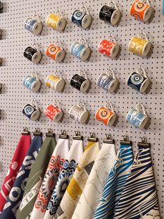 there are many different types of coffee cups hanging on the pegs in this shop