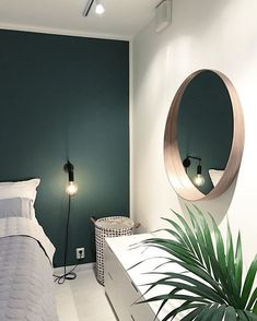 a bed room with a neatly made bed next to a mirror and a potted plant