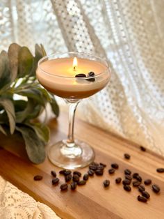 a glass filled with coffee sitting on top of a table next to a potted plant