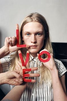 a woman holding up letters that spell out love in front of her face and fingers